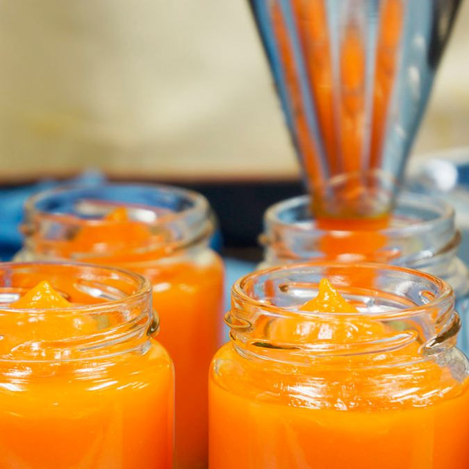 オレンジ色のジャムを瓶に詰める